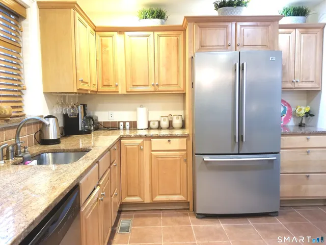 a kitchen with stainless steel appliances granite countertop a refrigerator a sink and white cabinets