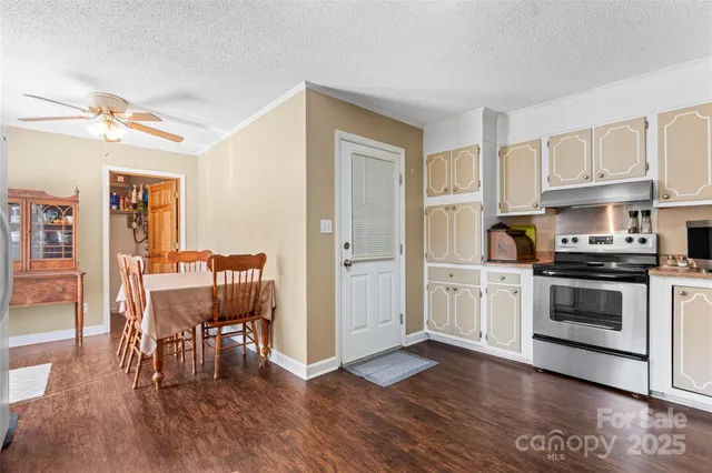 a kitchen with granite countertop a table chairs stove and cabinets