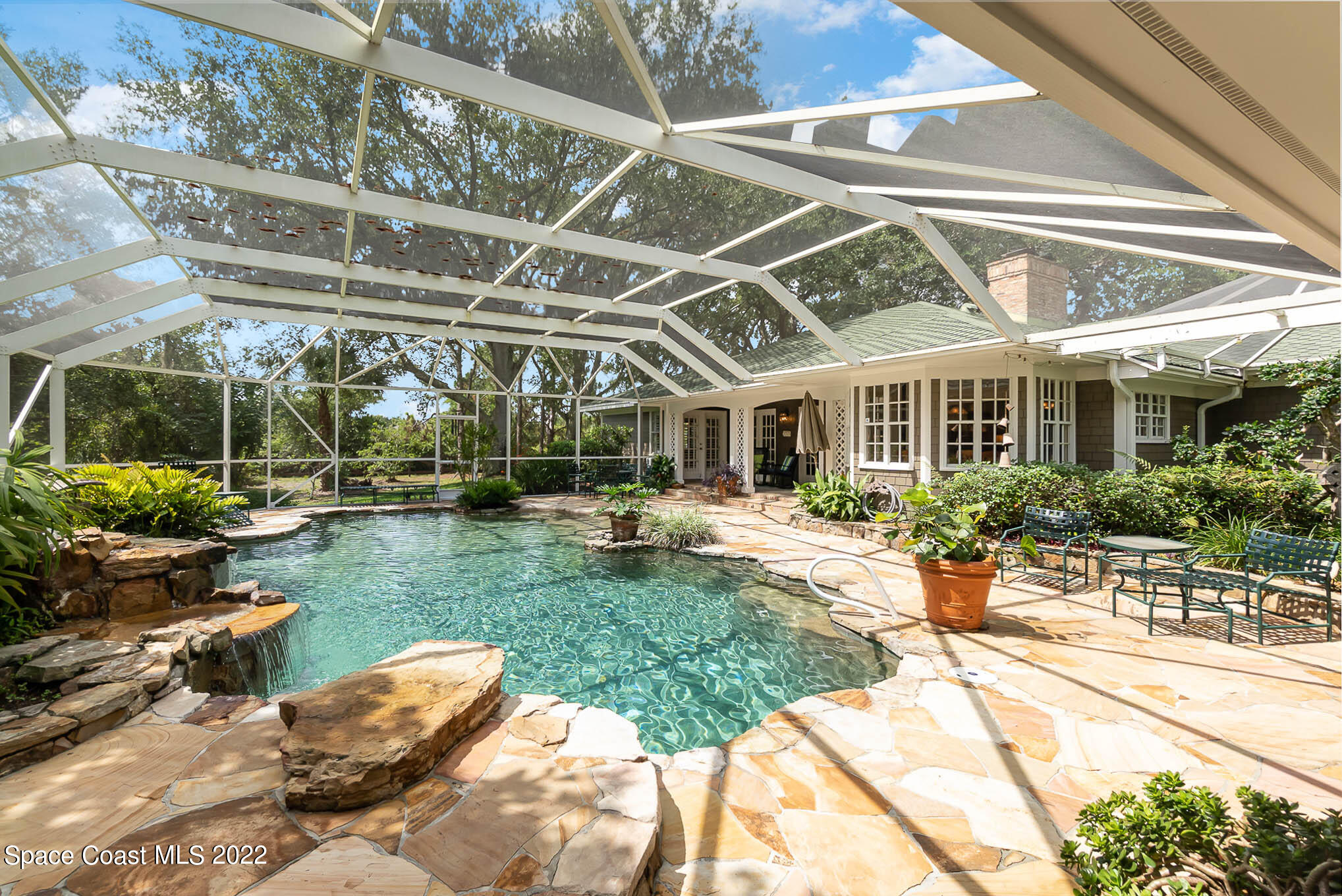 4025 Turtle Mound Road Melbourne, FL 32934 - Photo 23 of 54 a view of a patio with table and chairs potted plants and palm trees