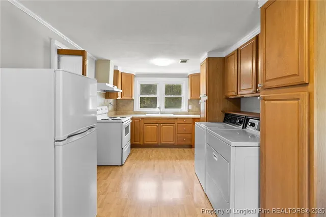 a kitchen with a refrigerator a stove top oven a sink and dishwasher with wooden floor