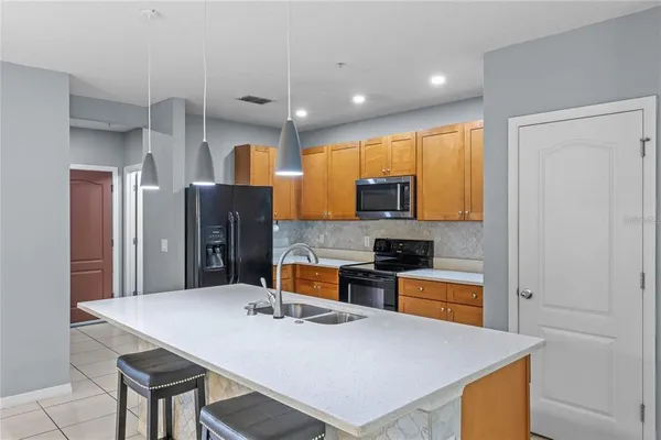 a kitchen with stainless steel appliances a refrigerator a stove a sink dishwasher with a dining table and chairs with wooden floor