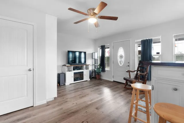a view of a livingroom with furniture a flat screen tv wooden floor and a ceiling fan