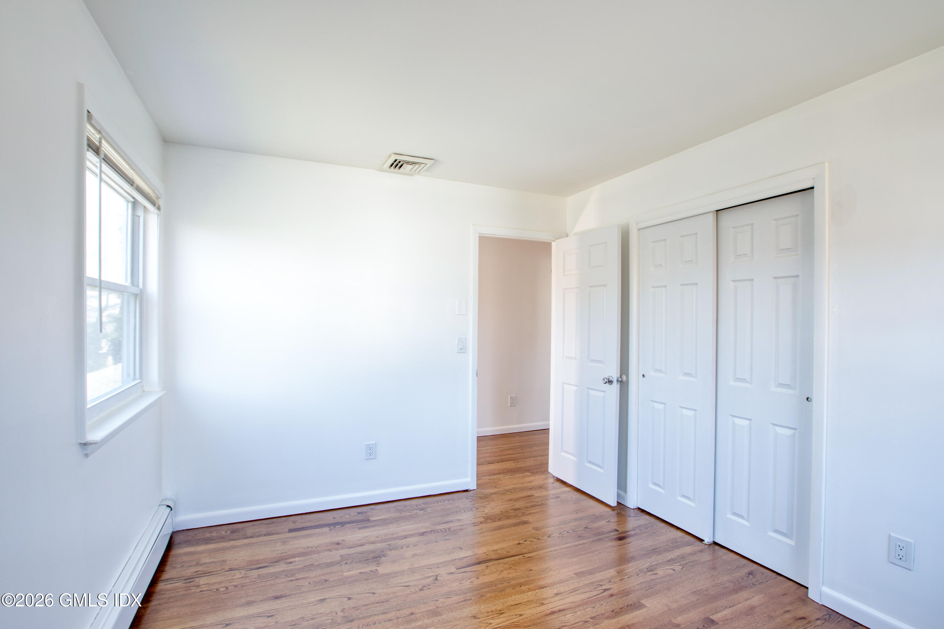 25 Alexander Street, Unit B Greenwich, CT 06830 - Photo 11 of 26 a view of an empty room with wooden floor and a window
