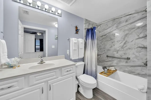 a bathroom with a sink a toilet a mirror a bathtub and shower