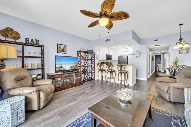 a living room with furniture kitchen view and a wooden floor
