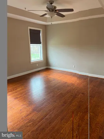 an empty room with wooden floor fan and windows