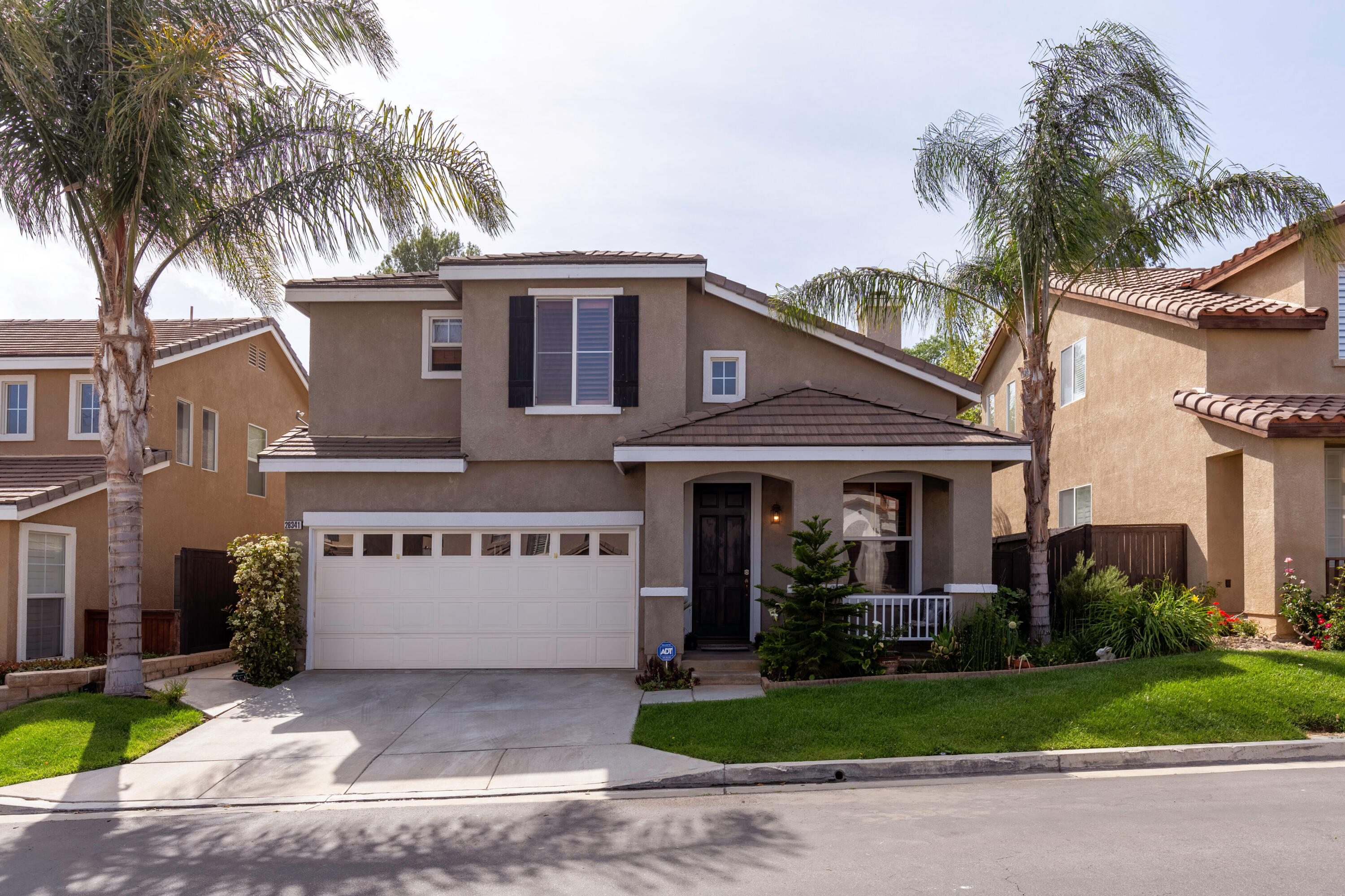 a front view of a house with a garden and palm trees