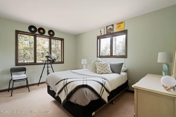 a bedroom with a bed a dresser next to a window
