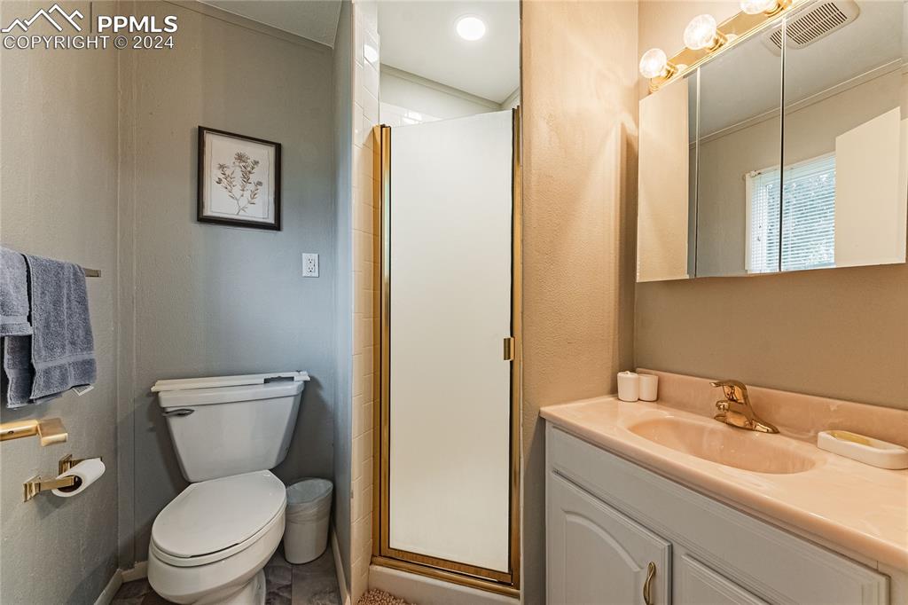1407 Alexander Road Colorado Springs, CO 80909 - Photo 15 of 27 a bathroom with a toilet sink and mirror