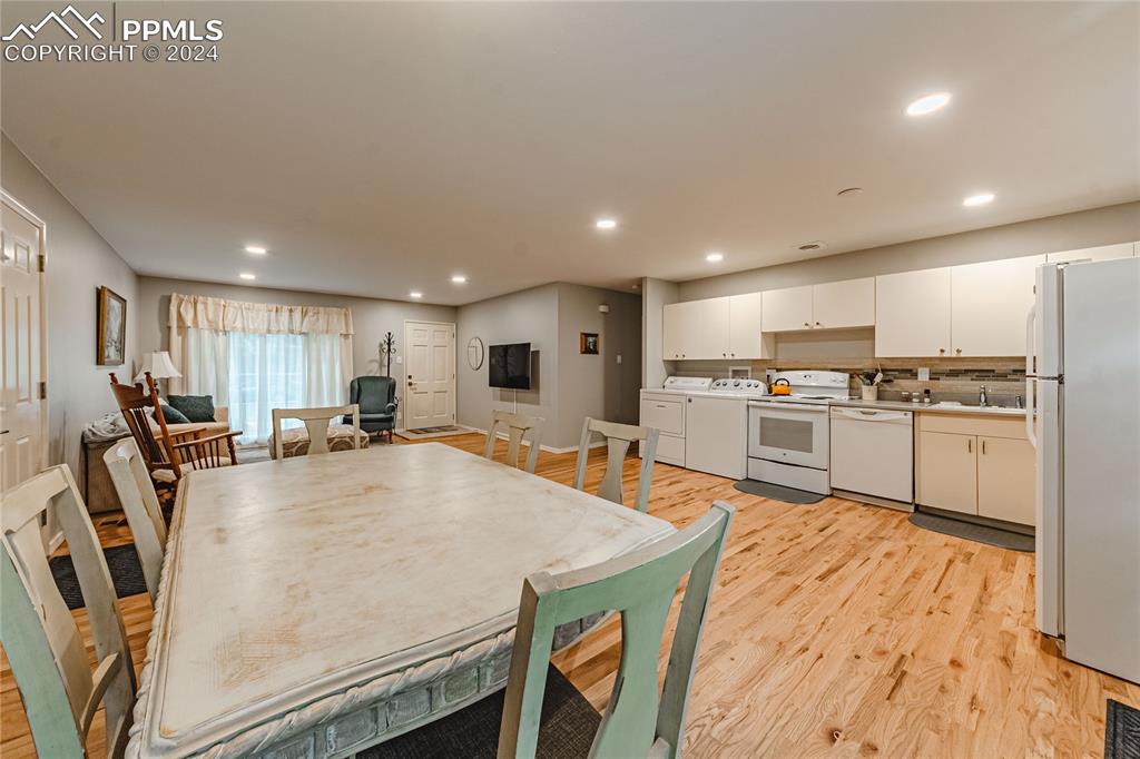 1407 Alexander Road Colorado Springs, CO 80909 - Photo 8 of 27 a large kitchen with kitchen island a stove a sink a refrigerator and white cabinets with wooden floor