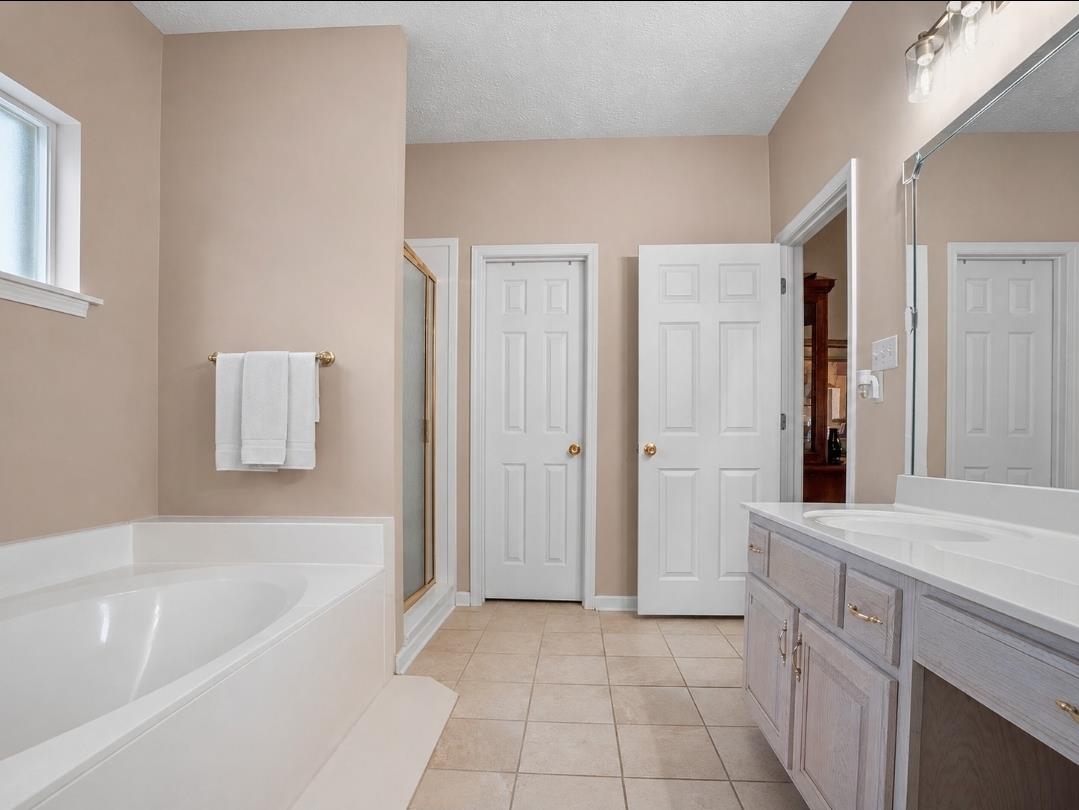 3779 Dancyville Road Stanton, TN 38069 - Photo 11 of 22 Bathroom featuring a built-in soaking tub, a stand-up shower with a glass enclosure, and a double vanity with an integrated sink