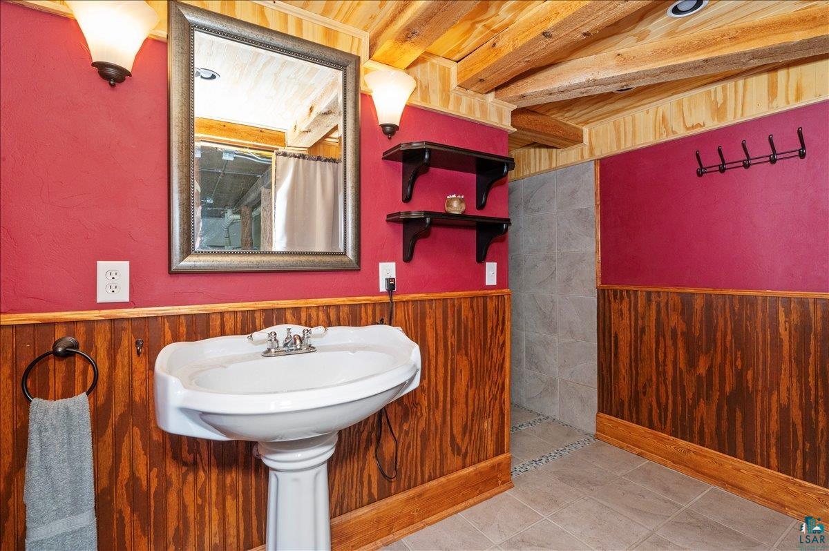 7596 Werner Road Virginia, MN 55792 - Photo 13 of 27 Pedestal sink with chrome faucet, set against wood-finish wainscoting and a deep red wall