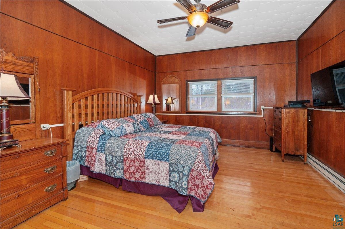 7596 Werner Road Virginia, MN 55792 - Photo 15 of 27 Room featuring wood-finish paneling, hardwood flooring, and a ceiling fan with integrated lighting