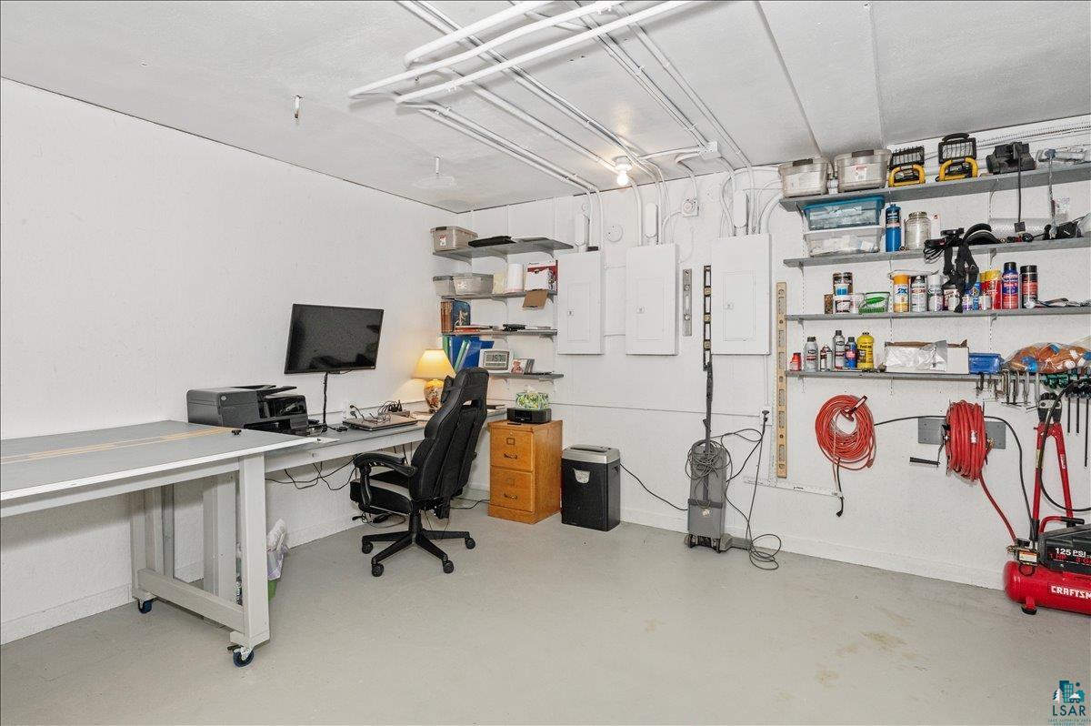 7596 Werner Road Virginia, MN 55792 - Photo 18 of 27 Flexible basement space featuring painted concrete flooring, extensive wall shelving for storage, multiple electrical panels, and exposed ceiling utilities