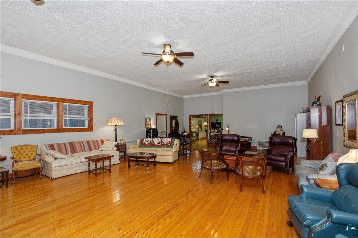 7596 Werner Road Virginia, MN 55792 - Photo 2 of 27 Spacious common area featuring wood-finish flooring, high ceilings with crown molding, and multiple windows with wood-trimmed frames