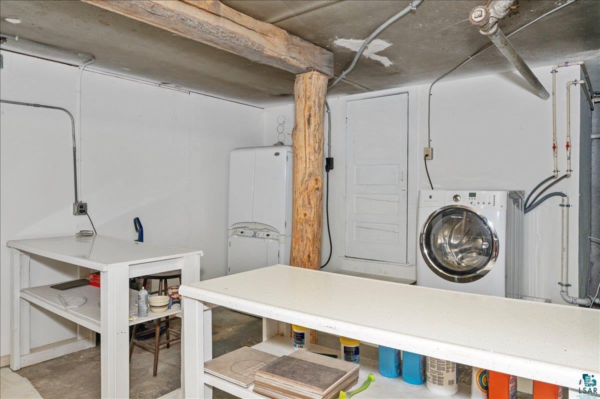 7596 Werner Road Virginia, MN 55792 - Photo 22 of 27 Utility area featuring a front-loading washing machine, exposed wood beam, and concrete flooring
