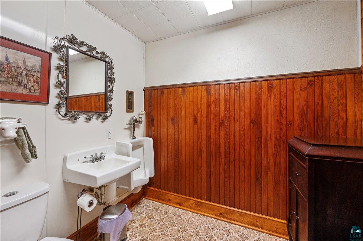 7596 Werner Road Virginia, MN 55792 - Photo 23 of 27 Restroom featuring wood paneling, a wall-mounted sink, and patterned floor tiles