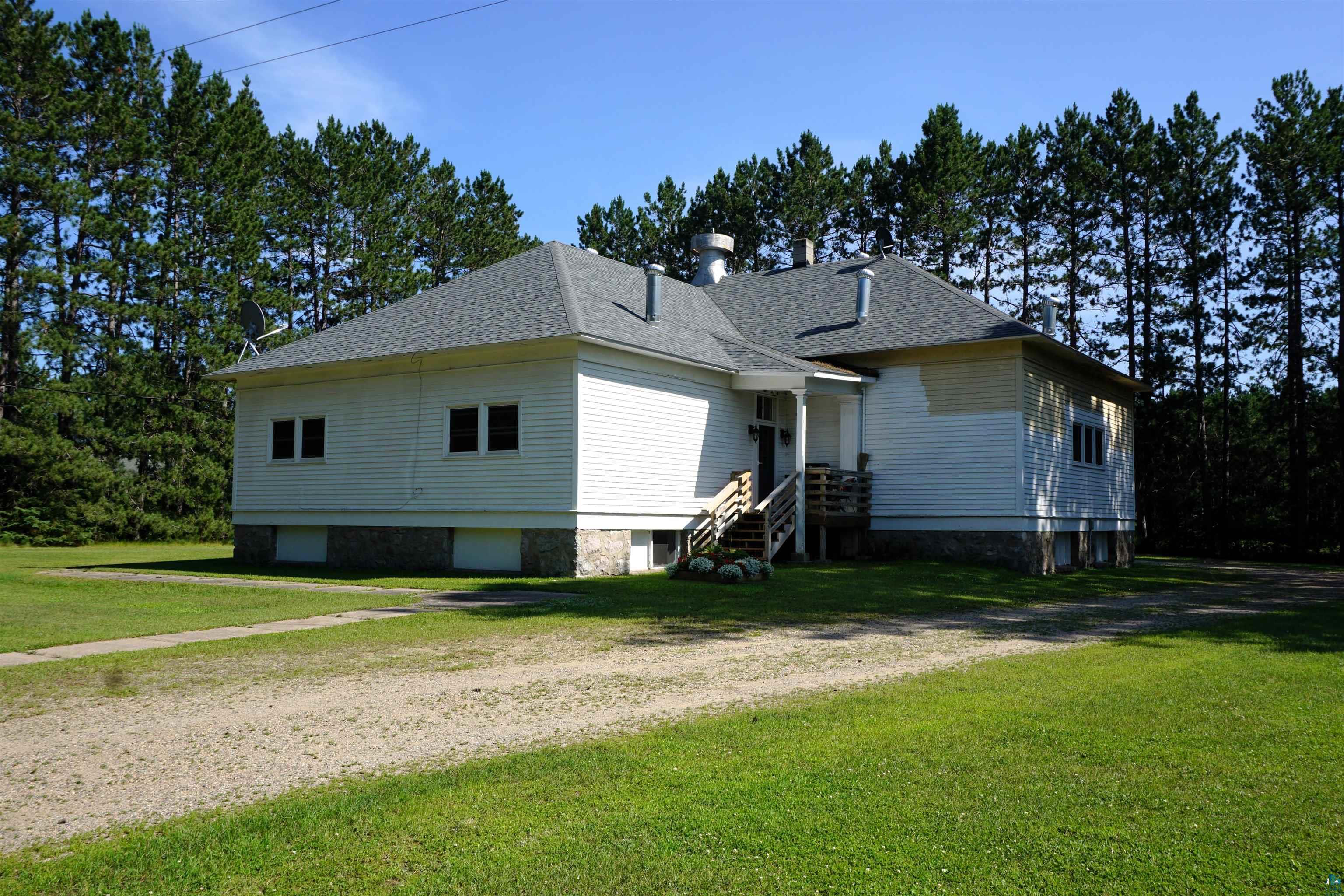7596 Werner Road Virginia, MN 55792 - Photo 25 of 27 White clapboard siding exterior with a stone foundation, a gray shingle roof, and multiple windows