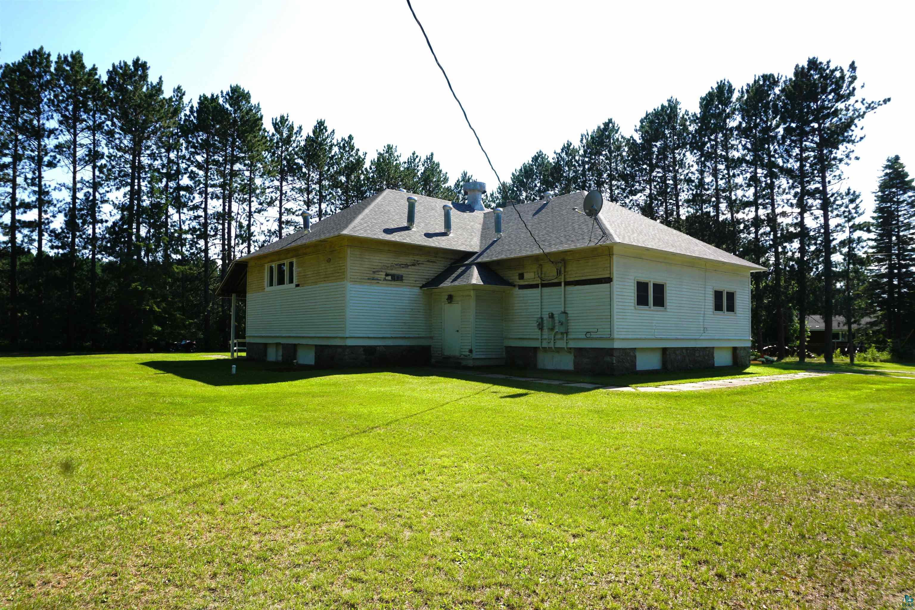 7596 Werner Road Virginia, MN 55792 - Photo 26 of 27 Expansive green lawn surrounds a property featuring a multi-level roofline, white horizontal siding, and a stone foundation