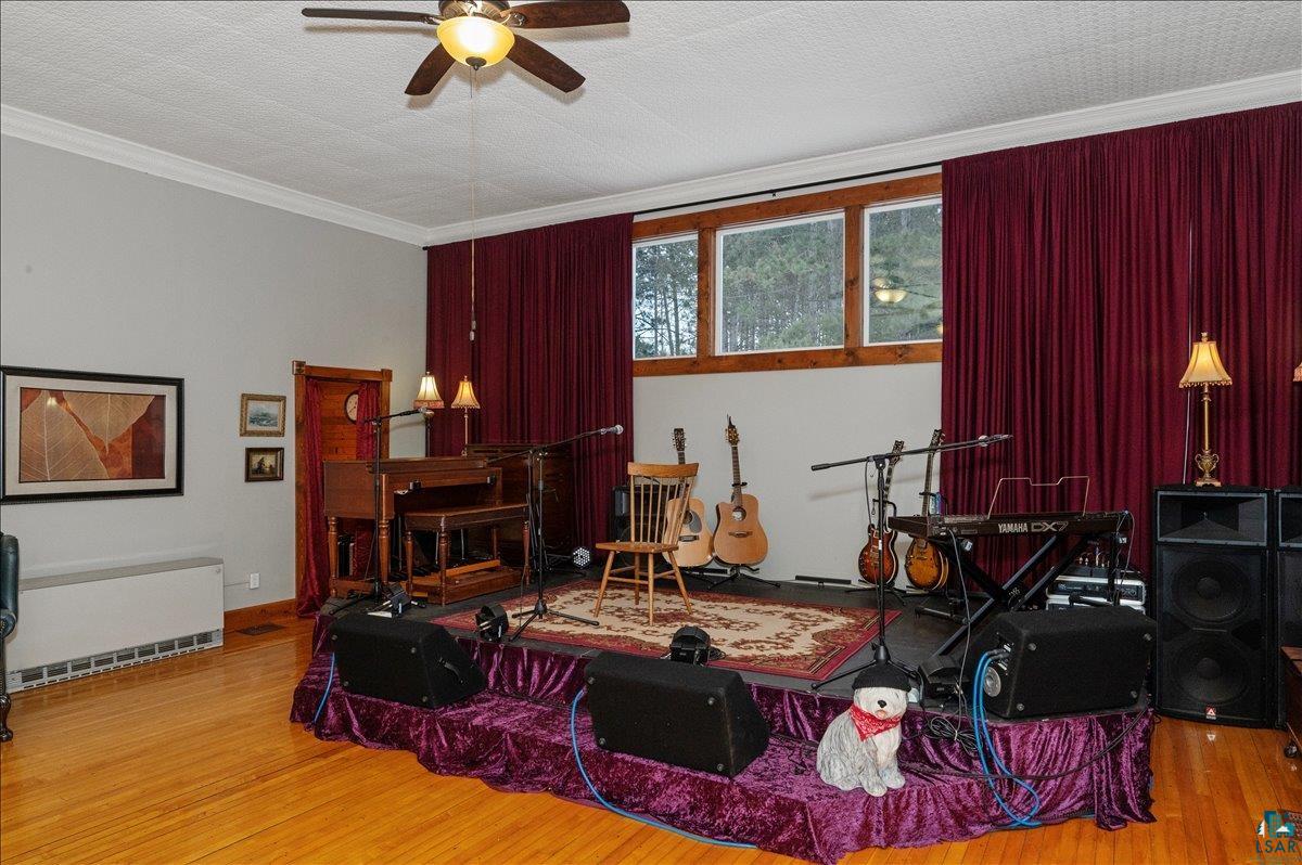 7596 Werner Road Virginia, MN 55792 - Photo 4 of 27 Spacious room featuring wood-finish flooring, a ceiling fan, and multiple windows with deep red drapes