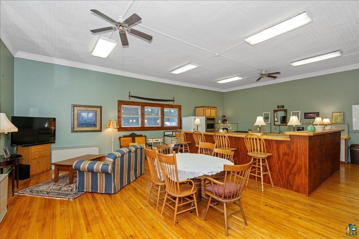 7596 Werner Road Virginia, MN 55792 - Photo 6 of 27 Spacious common area featuring wood-finish flooring, a wood-paneled bar with seating, recessed fluorescent lighting, and ceiling fans