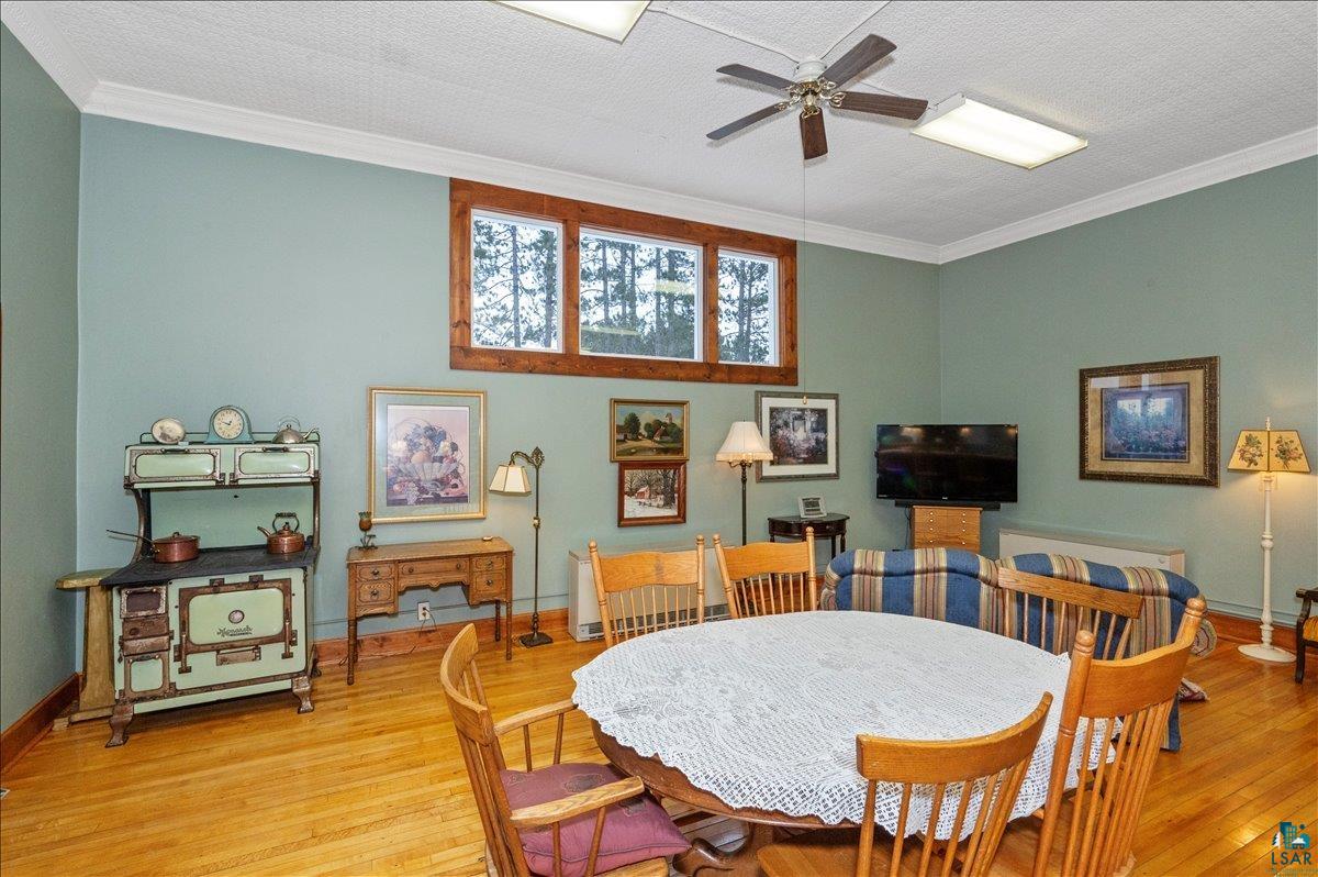 7596 Werner Road Virginia, MN 55792 - Photo 7 of 27 Open-concept room featuring wood-finish flooring, a ceiling fan, crown molding, and a high window bank with natural wood trim