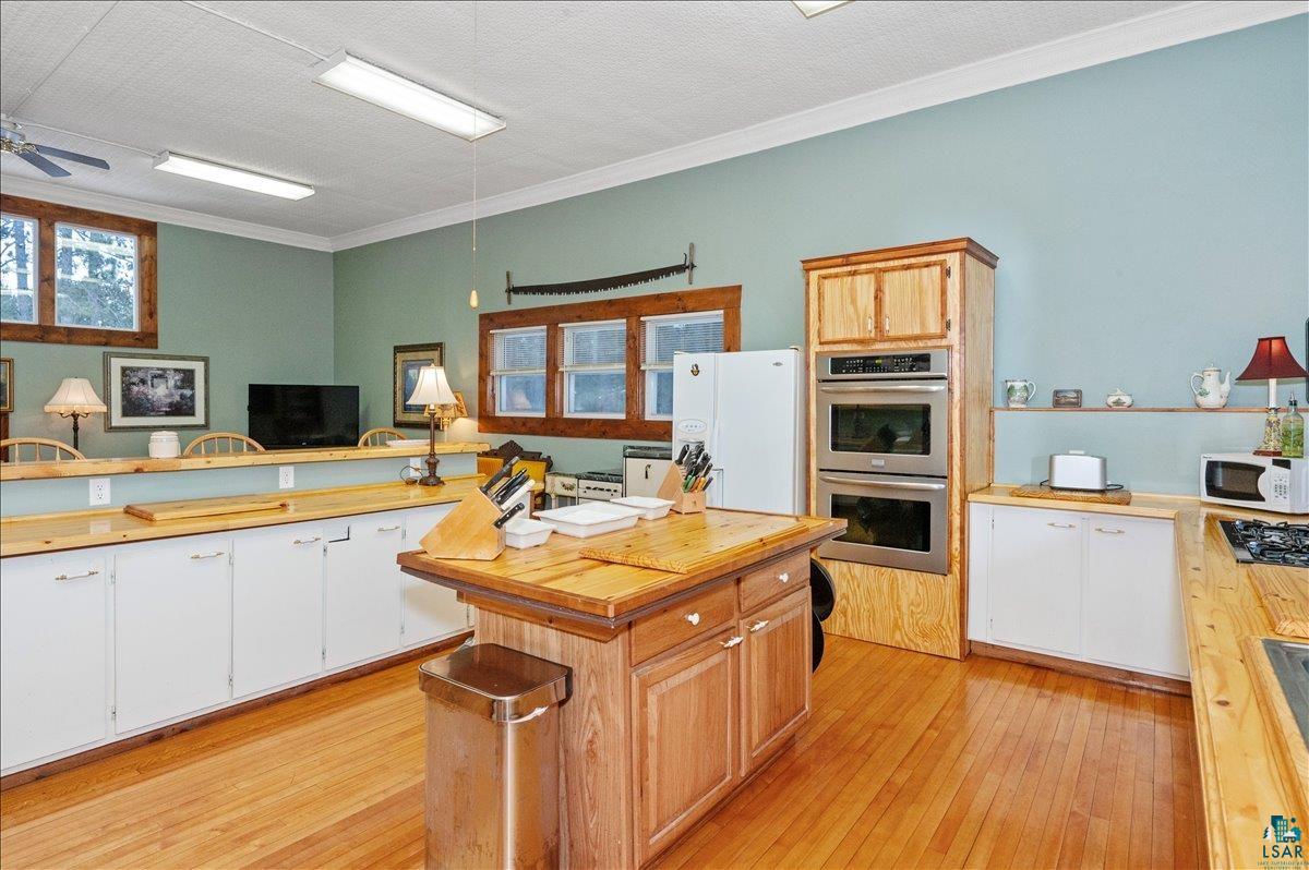 7596 Werner Road Virginia, MN 55792 - Photo 9 of 27 Spacious kitchen featuring wood-finish flooring, a central island with a wood countertop, white cabinetry with wood-finish countertops, and built-in double ovens