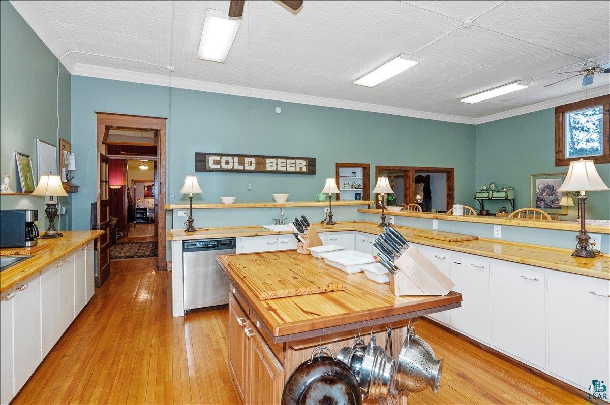 7596 Werner Road Virginia, MN 55792 - Photo 10 of 27 Spacious kitchen featuring a central wood-finish island, extensive wood-finish countertops, white cabinetry, hardwood flooring, and stainless steel appliances