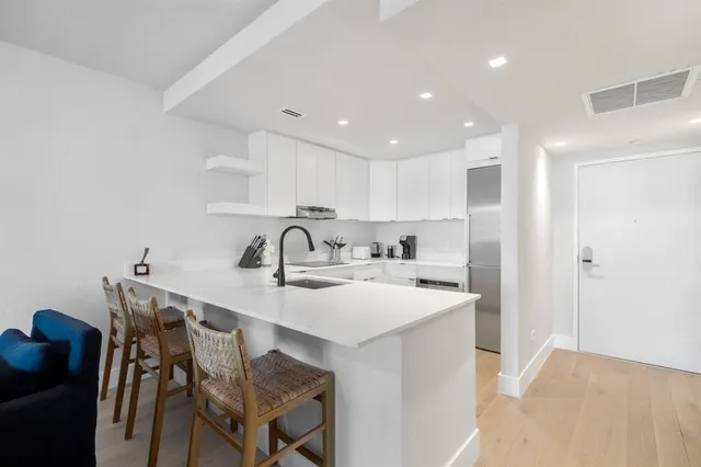 a kitchen with stainless steel appliances granite countertop a sink a stove a refrigerator and island