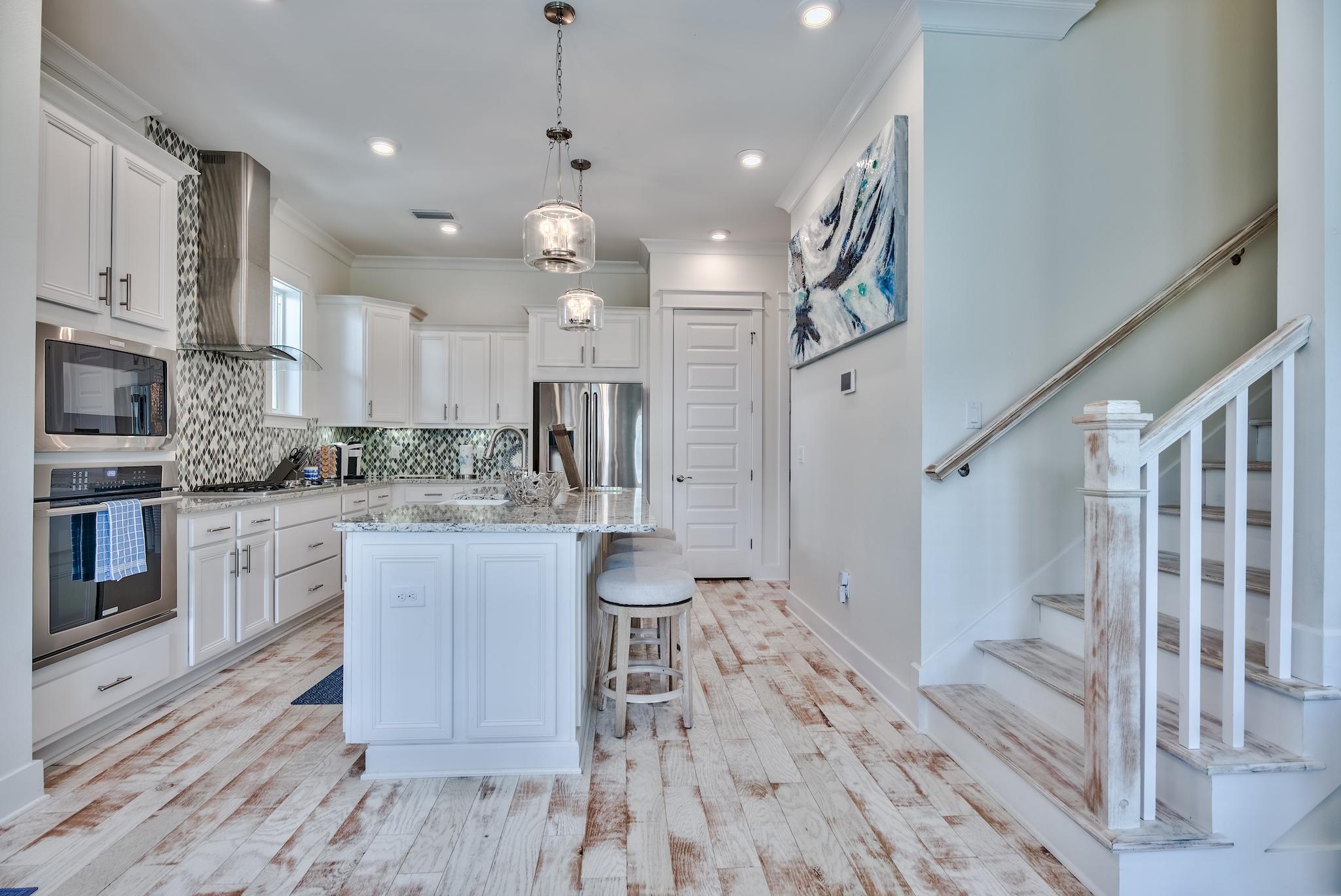 308 Milestone Dr Inlet Beach, Unit B Inlet Beach, FL 32461 - Photo 7 of 49 a kitchen with stainless steel appliances kitchen island granite countertop a refrigerator a stove a sink and white cabinets with wooden floor