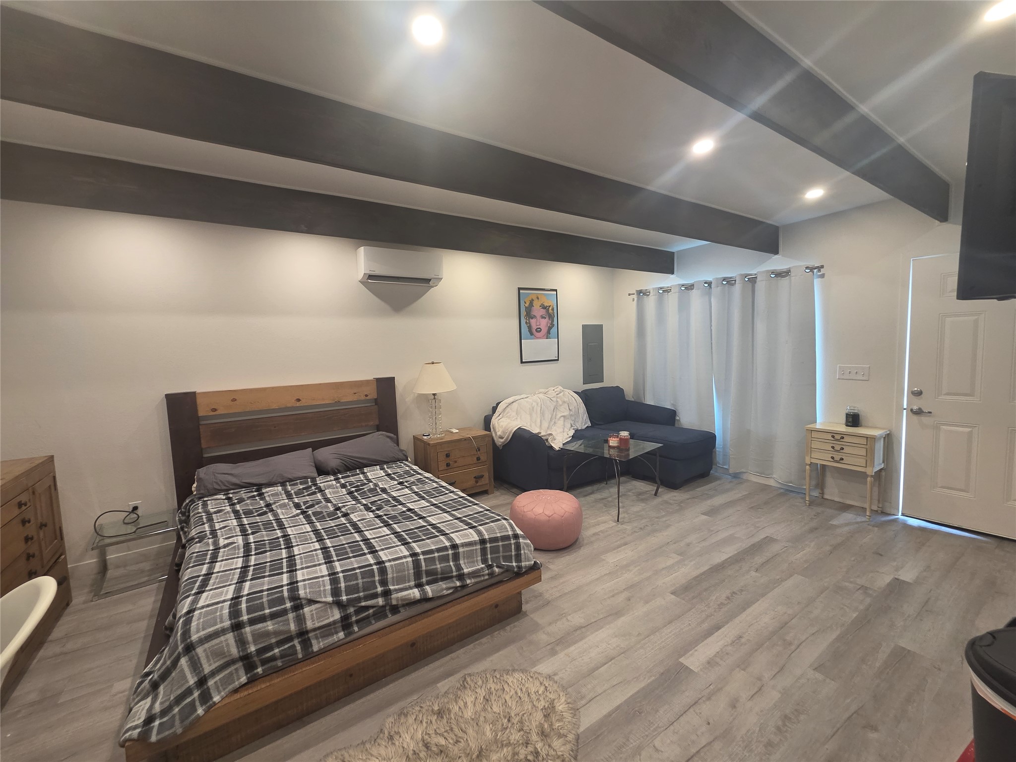 1106 The High Road, Unit B Austin, TX 78746 - Photo 5 of 8 Exposed ceiling beams enhance this cozy bedroom with light wood flooring.
