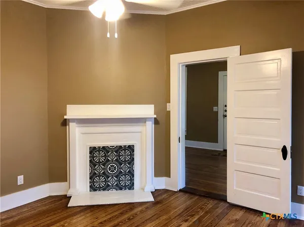 a view of an empty room with wooden floor and a fireplace