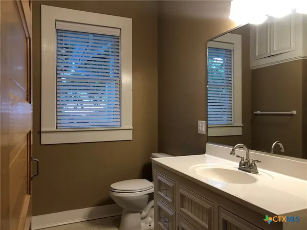 a bathroom with a granite countertop sink toilet and mirror