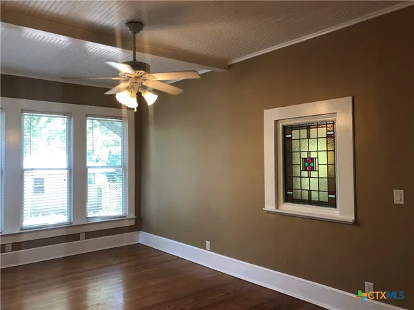 a view of an empty room with wooden floor and a window