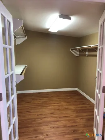 a view of an empty room with wooden floor and windows