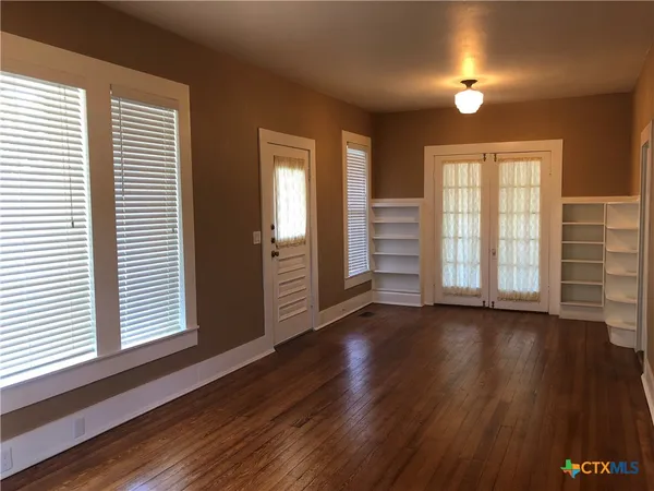 an empty room with wooden floor and windows