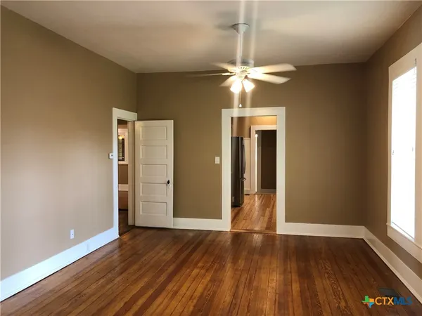a view of an empty room with wooden floor and a window