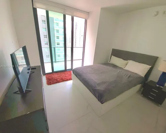 a bedroom with a bed a mirror and a large window