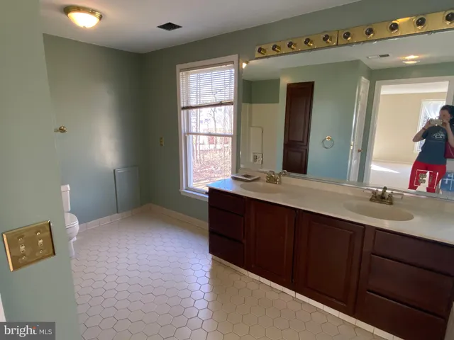 a bathroom with a double vanity sink toilet mirror and bathtub