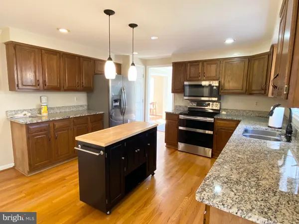 a kitchen with stainless steel appliances granite countertop wooden cabinets a stove top oven a sink and dishwasher