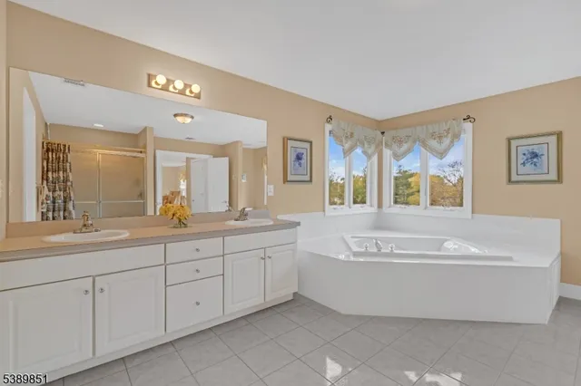 a spacious bathroom with a tub double sink mirror and window