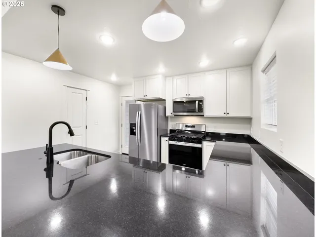 a kitchen with stainless steel appliances granite countertop a sink a stove and a refrigerator