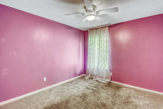 an empty room with windows and ceiling fan