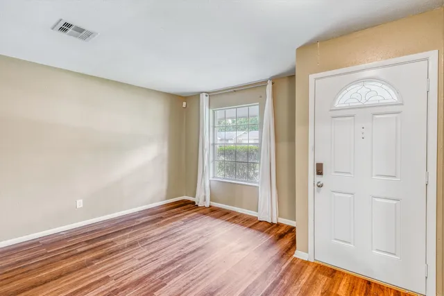 a view of empty room with wooden floor and fan