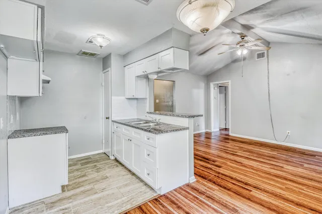 a kitchen with granite countertop a stove and a wooden floor