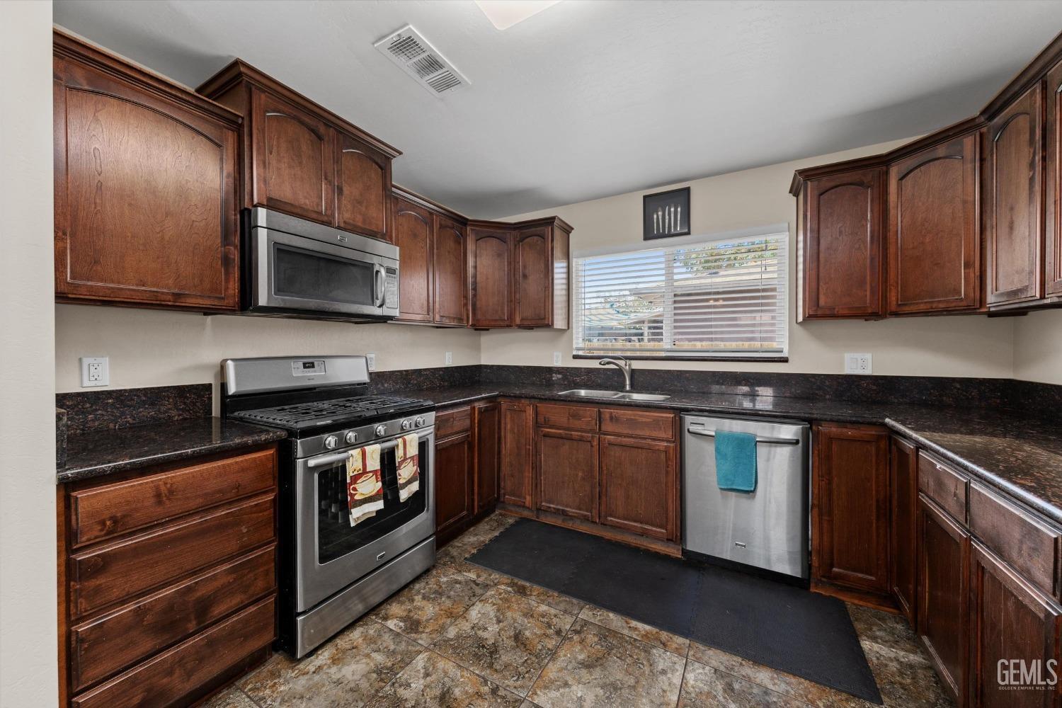 Undisclosed Address Bakersfield, CA 93309 - Photo 14 of 31 a kitchen with stainless steel appliances granite countertop wooden cabinets a stove top oven a sink and dishwasher