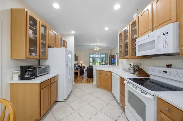 a living room with kitchen island granite countertop wooden floor and a refrigerator