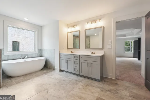 a spacious bathroom with a double vanity sink mirror and bathtub
