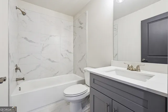 a bathroom with a granite countertop sink a toilet and a mirror
