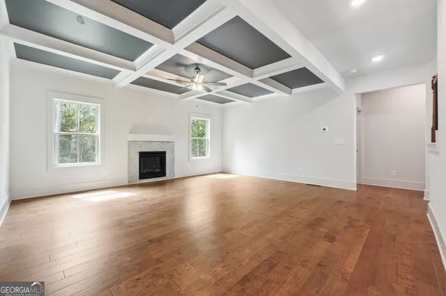an empty room with windows fireplace and a kitchen view